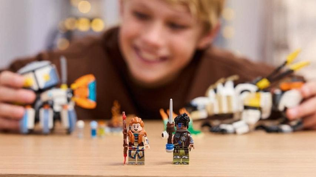 Two Horizon Lego minifigures stand on a table. 